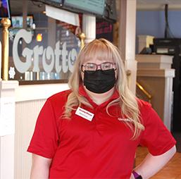 Woman with Down Syndrome wearing a Grottos Pizza Polo smiles at the camera