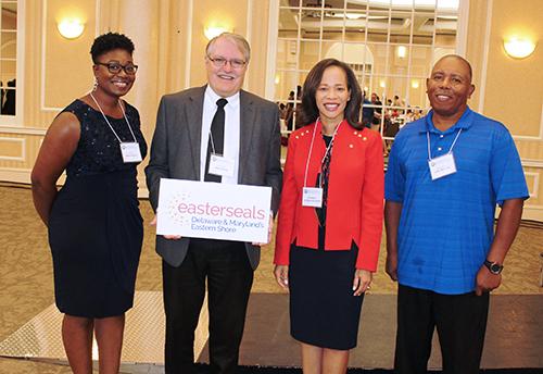 Easterseals CEO and legislators stand with Direct Support Professionals and smile at the camera.