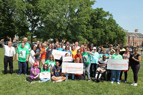 A large group of people with disabilities and advocates gather on the Green in Dover holding Easterseals Signs.