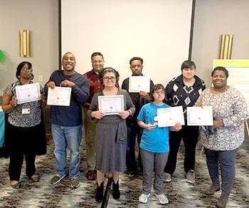 group of participants hold up certificates for volunteerism