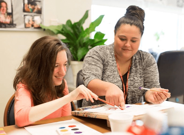 Direct support professional painting with a participant with an intellectual disability