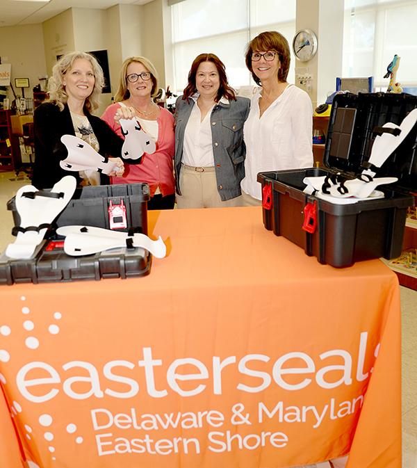 A group of people stand around a table displaying assistive swimming technology.