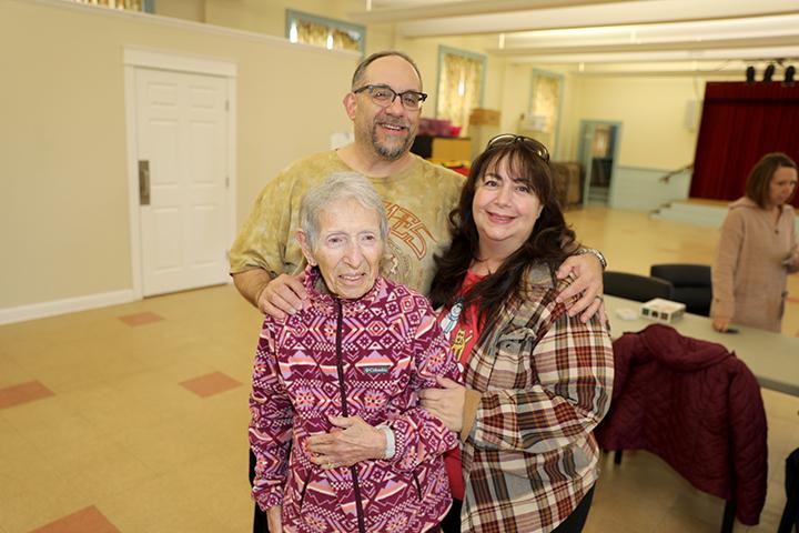 Three people smile at the camera in a church-like setting