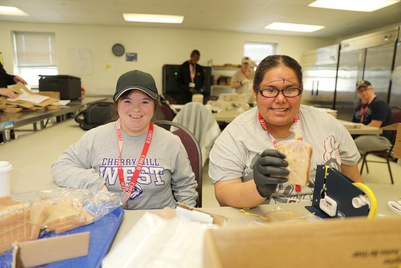 two adults with I/DD working to package sandwiches