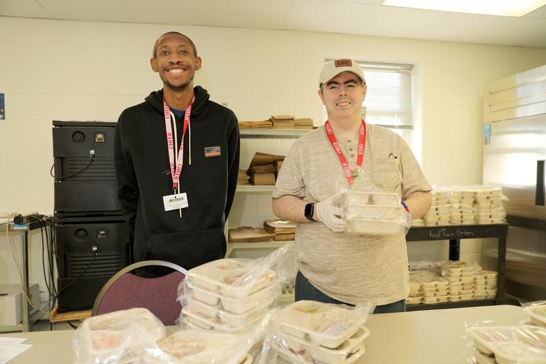 2 adults working to package lunches for seniors