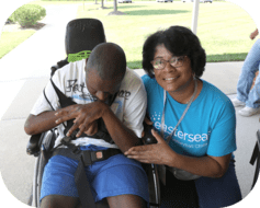 A direct support professional sitting next to a man with disabilities in a wheelchair