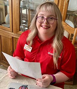 Woman with Down Syndrome wearing a Grottos Pizza Polo smiles at the camera