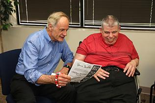 Legislator reads from paper while talking to a participant who is blind and has a hearing impairment