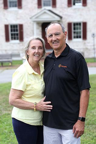 A man and a woman stand in front of Camp Fairlee Manor. They are smiling at the camera.