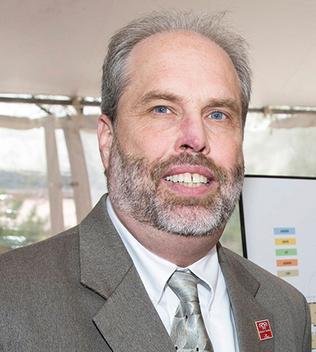 Headshot of a man who is wearing a gray suit