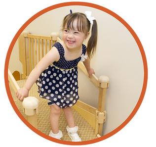 A child with ponytails smiles while walking on a physical therapy staircase