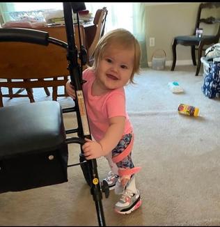 young girl with leg braces on holding onto a chair