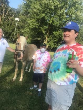 Young adult man with a disability standing next to a horse