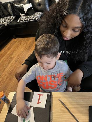 A child touching numbered cards while a specialist looks after him