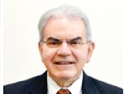 a headshot of a man. He is wearing a dark blazer and a reddish tie.