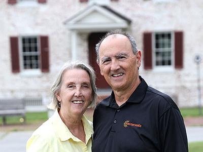 A man and a woman stand in front of Camp Fairlee Manor. They are smiling at the camera.