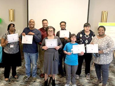 group of participants hold up certificates for volunteerism