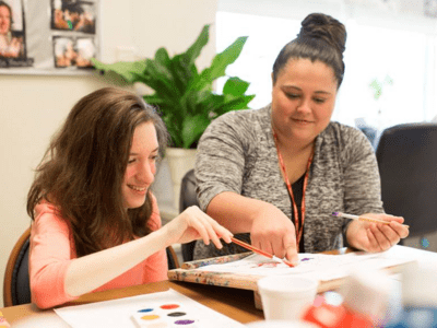 Direct support professional painting with a participant with an intellectual disability