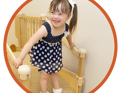 A child with ponytails smiles while walking on a physical therapy staircase