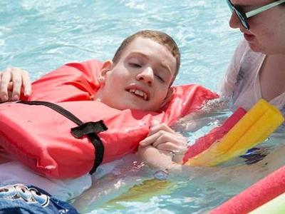 A man with a disability in a swimming pool with his counselor