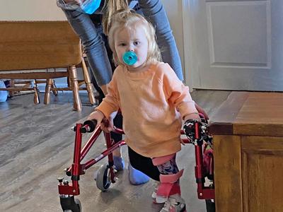 young girl in a walker with an adult female helping