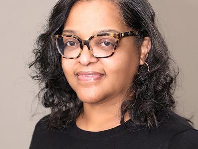 Headshot of woman with curly black hair and tortoise shell glasses