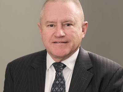 A man in a suit and tie smiles at the camera