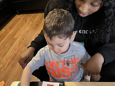 A child touching numbered cards while a specialist looks after him