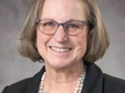 Headshot of a smiling woman with glasses and short blond hair