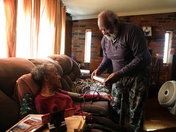 A husband is checking the heart rate of his wife who has had a stroke