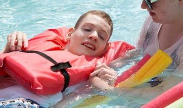 A man with a disability in a swimming pool with his counselor